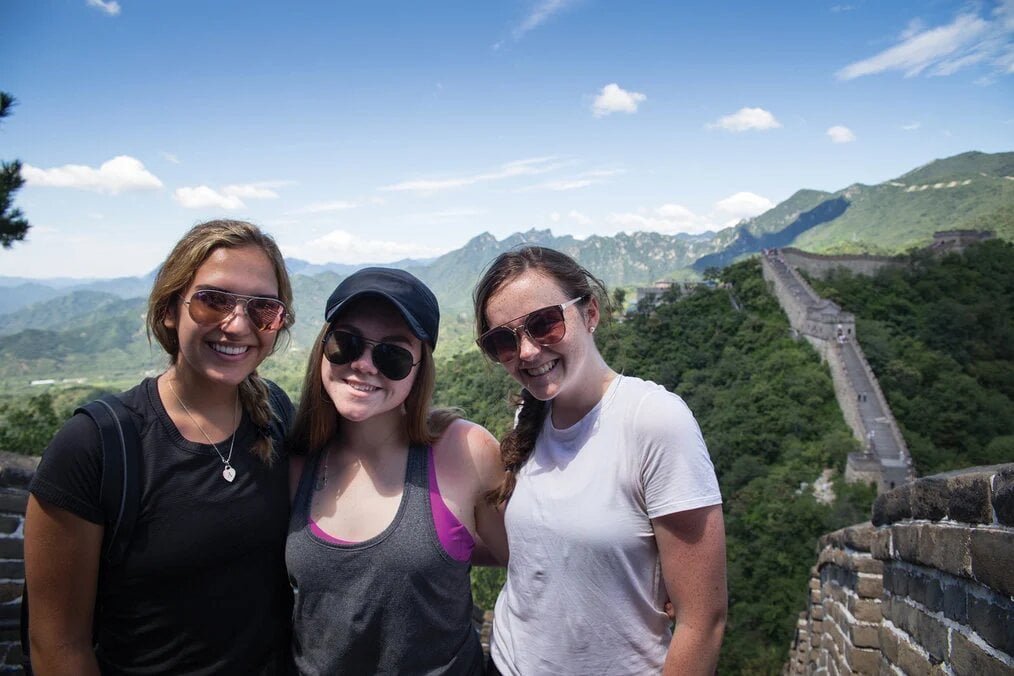 Great Wall MEI Three high school girls smile with the Great Wall of China in the background.
